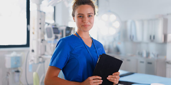 Eine Pflegewissenschaftlerin im Behandlungsraum hält eine Tablet.