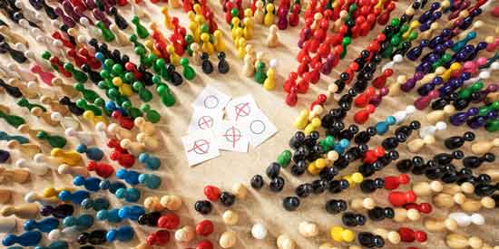 Viele bunte Spielfigure, rund um einen kleinen Haufen Stimmzettelchen